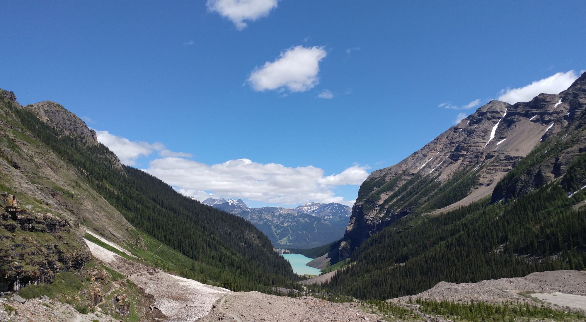 A wide Canadian Rockies valley opening onto a turquoise glacial lake far below